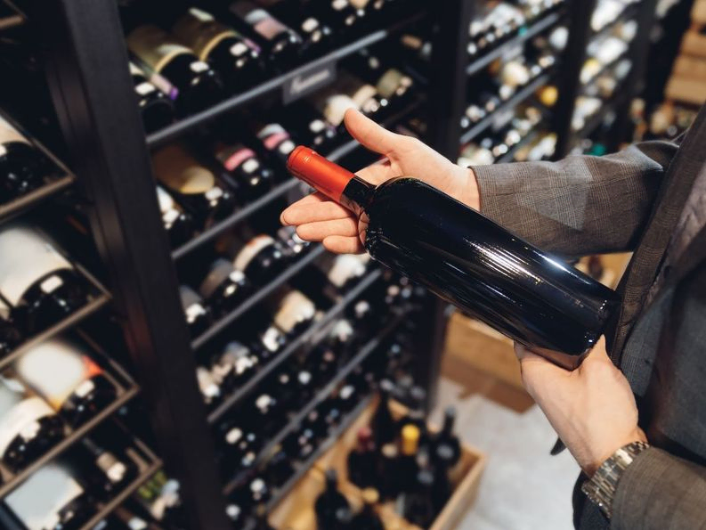 Hommbre tomando una botella de almacen de vinos